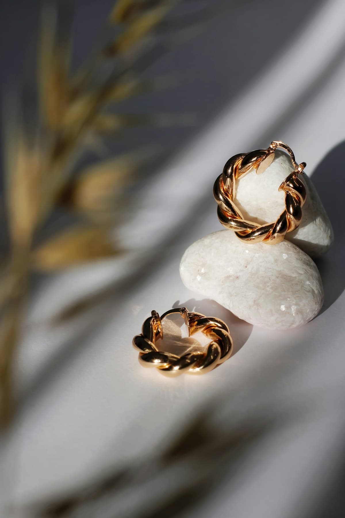 Sculptural gold twist hoops resting on pale stones